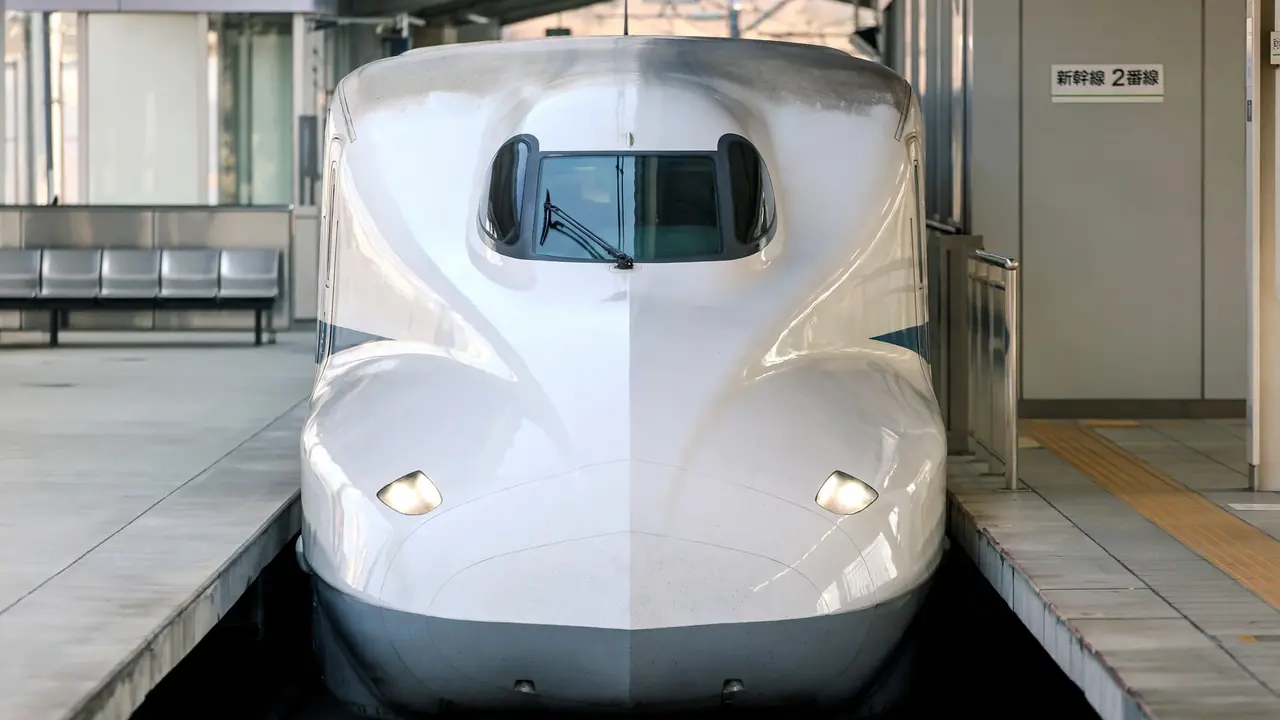 A white shinkansen bullet train at a station platform in Japan